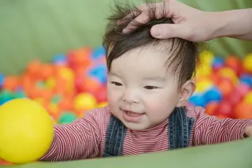 色とりどりのボールが並ぶ遊び場で、笑顔を見せる赤ちゃん