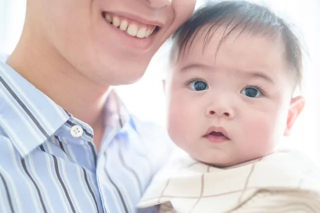 笑顔の大人に抱っこされ、頬を寄せている赤ちゃん